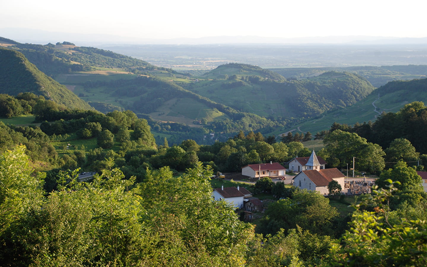 Vue panoramique de Labalme et de son église au cœur des paysages verdoyants du Bugey