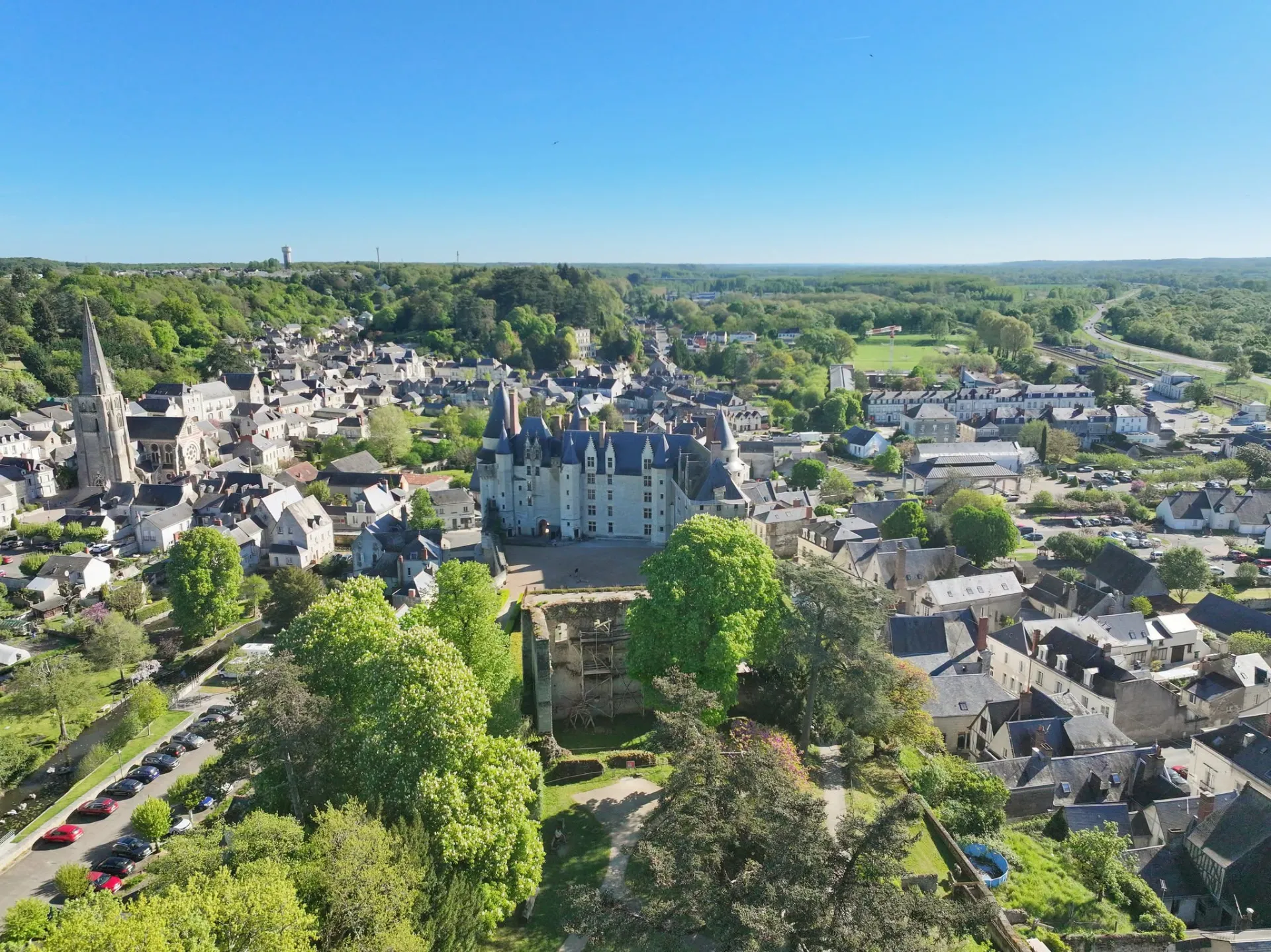 Vue aérienne de Langeais en Indre-et-Loire, avec le château au centre, l’église et les toits de la ville entourés de verdure.