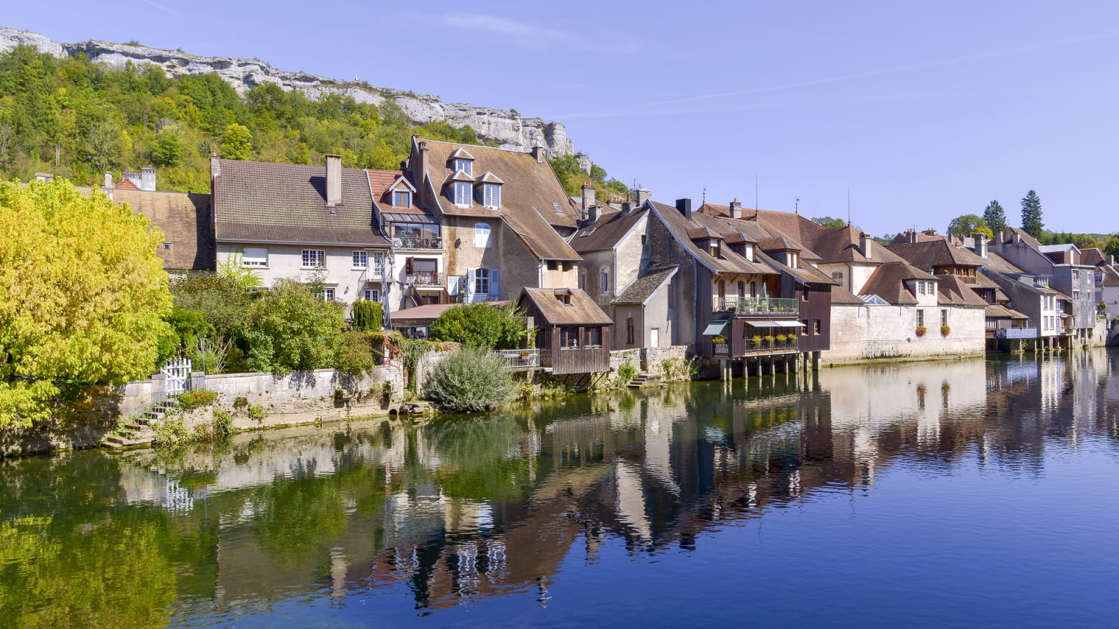 Maisons d’Ornans se reflétant dans la Loue au pied des falaises du Doubs