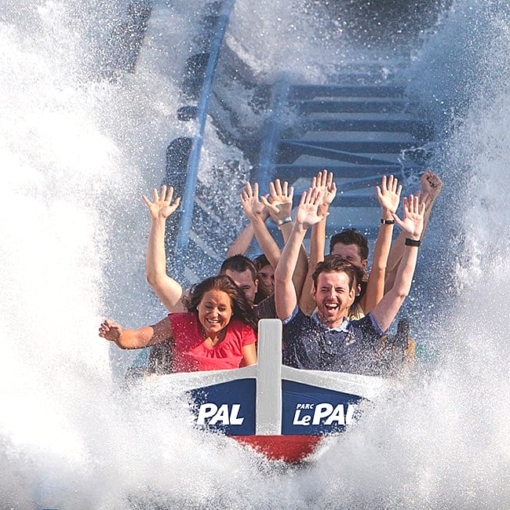Groupe de visiteurs les bras levés dans une attraction aquatique du Parc Le Pal éclaboussés par une grande vague