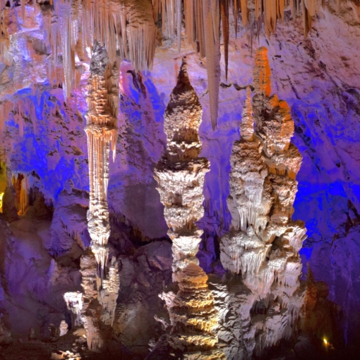 Stalactites et stalagmites géantes illuminées aux couleurs vives dans la Grotte de la Salamandre, joyau souterrain du Gard.