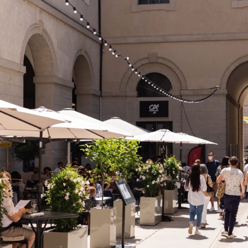 Terrasses animées et promeneurs sous les arches du Grand Hôtel-Dieu à Lyon, lieu emblématique du centre historique.