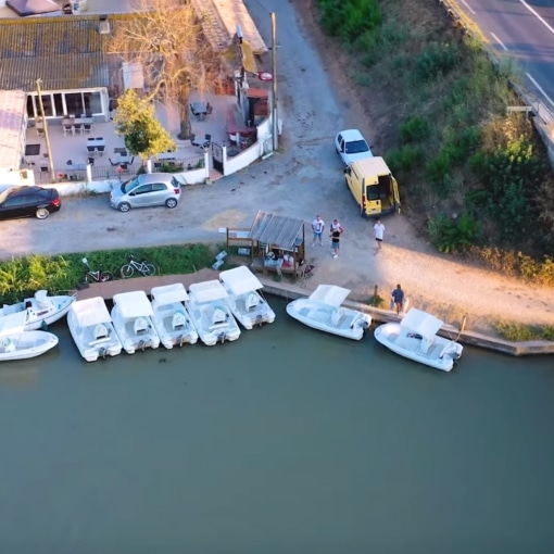 Vue aérienne d’un embarcadère avec plusieurs petits bateaux blancs amarrés au bord du Canal du Midi.