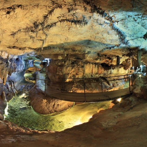 Passerelle suspendue au-dessus d’un bassin souterrain dans la Grotte de Labeil à Lauroux, joyau naturel des contreforts du Larzac.