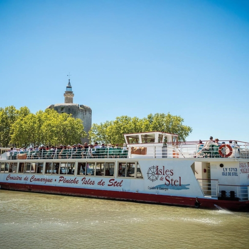 Péniche de la Croisière de Camargue naviguant sur les canaux d’Aigues-Mortes avec vue sur les remparts et la Tour de Constance