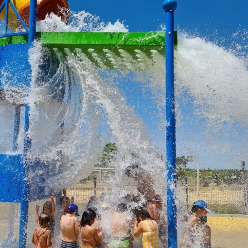 Jeunes enfants s’amusant sous une cascade géante d’eau au Green Park de Saint-Chaptes, parc de loisirs aquatiques en plein air.