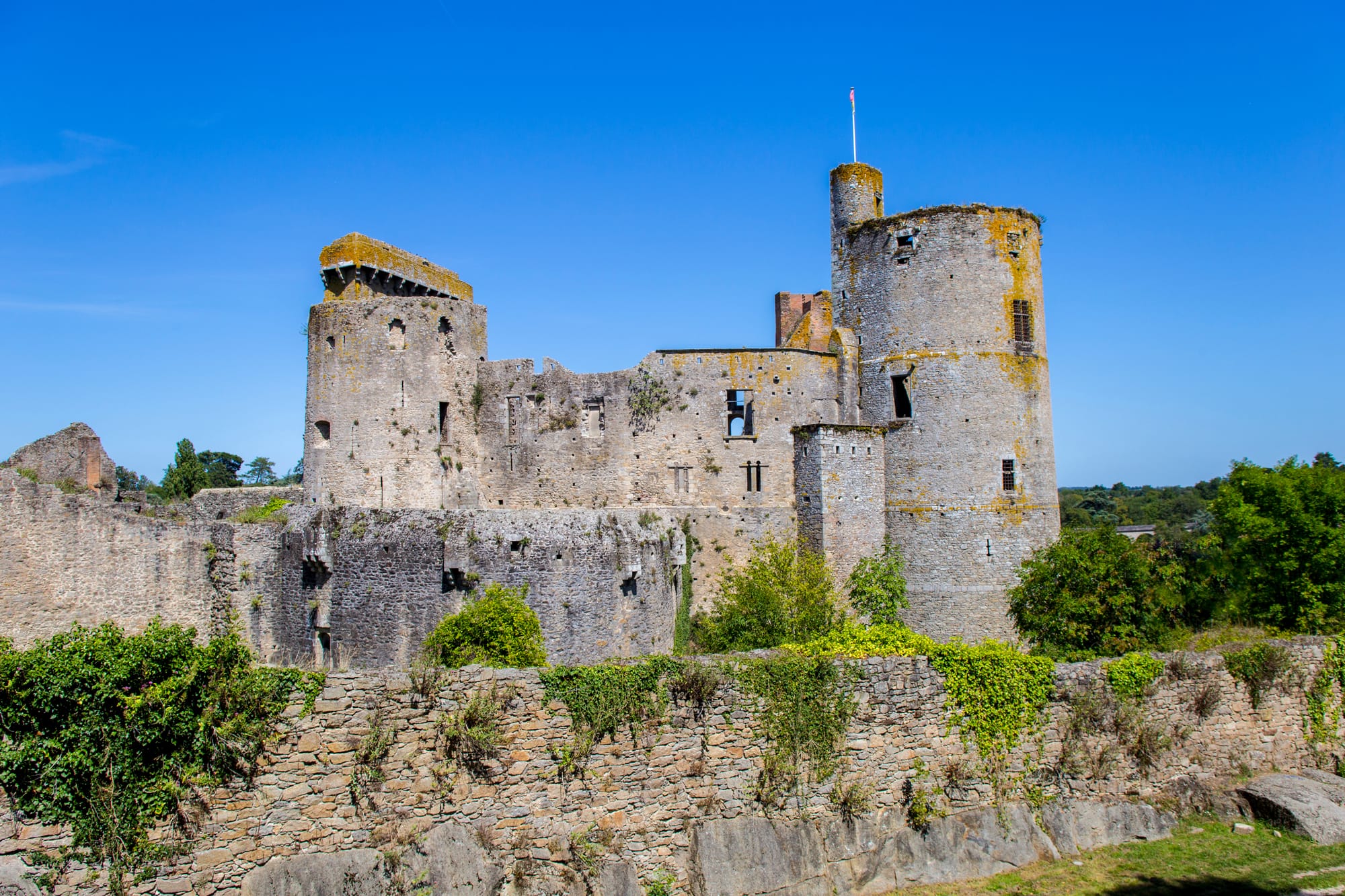 Vue du château de Clisson avec ses remparts et tours en pierre, vestige médiéval entouré de verdure sous un ciel bleu