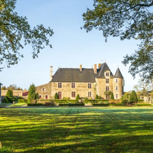 Vue du Logis de la Chabotterie, manoir de pierre à tours et toits d’ardoise, niché dans un écrin de verdure