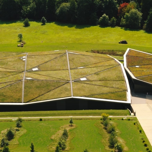 Vue aérienne de l’Historial de la Vendée, bâtiment moderne au toit végétalisé se fondant dans le paysage verdoyant