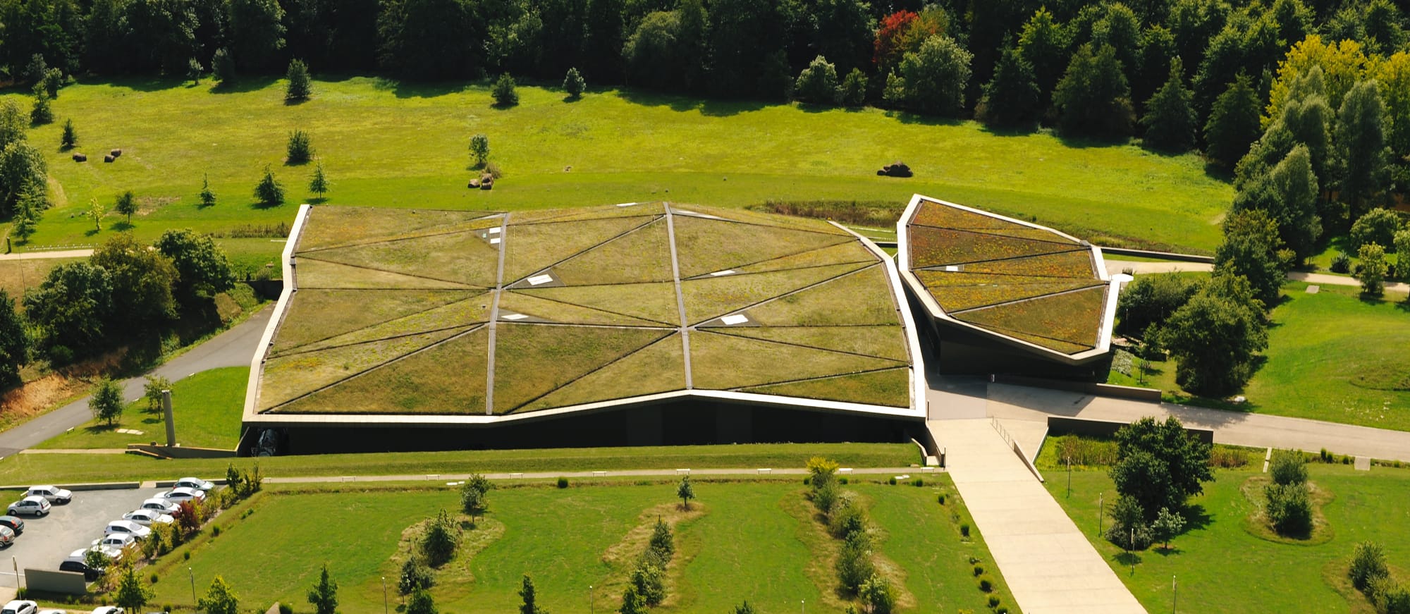 Vue aérienne de l’Historial de la Vendée, bâtiment moderne au toit végétalisé se fondant dans le paysage verdoyant
