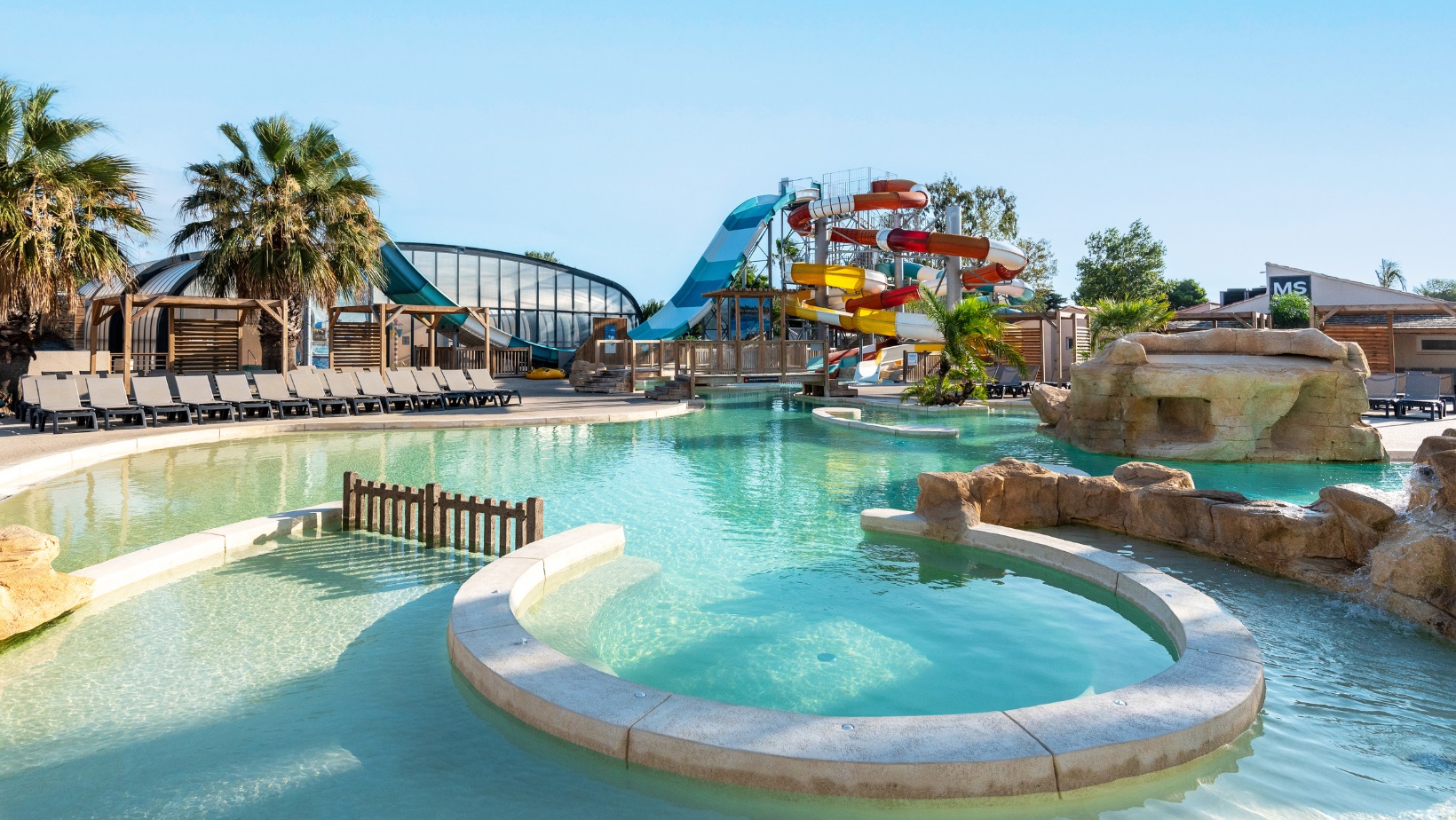 Parc aquatique du Camping Club Les Tamaris au Barcarès, avec piscines, toboggans et palmiers.