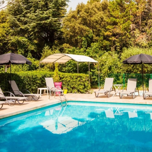 Piscine extérieure du Petit Manoir entourée d'un jardin arboré et d'espaces de détente en Provence.